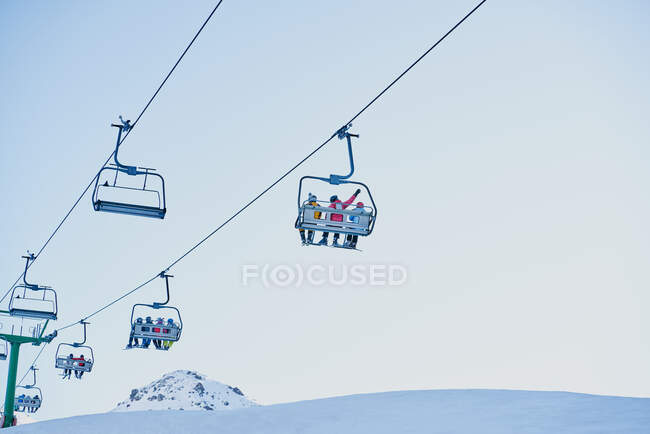 Esquiadores em um teleférico olhando para baixo com um fundo azul — Fotografia de Stock