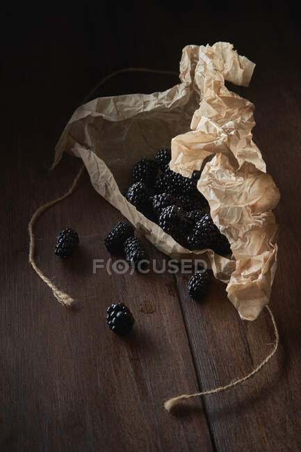 Черные ягоды, вылитые на стол из бумажной упаковки — стоковое фото