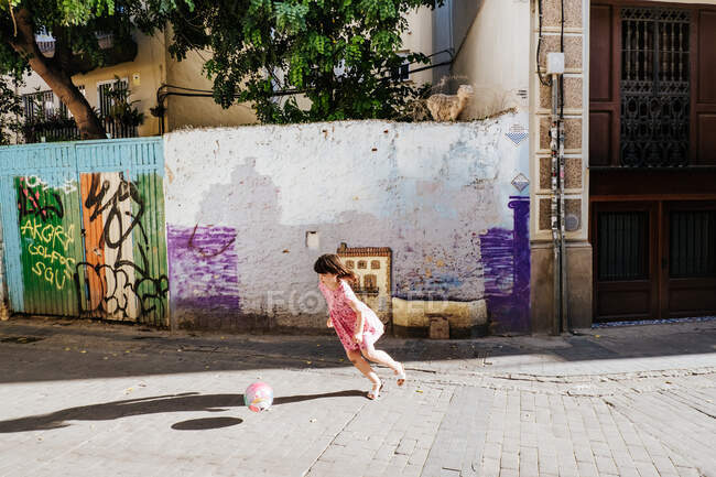 Menina jogando futebol / futebol em uma rua colorida — Fotografia de Stock