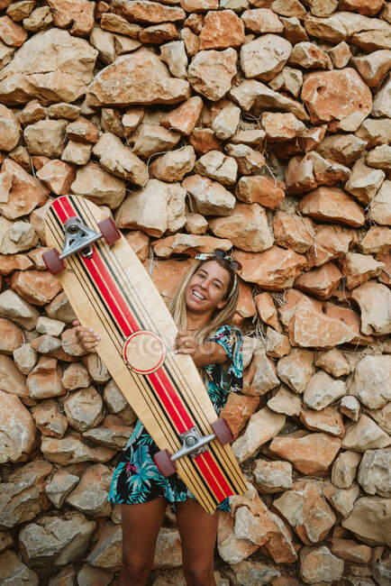 Jeune femme heureuse avec skateboard et lunettes de soleil — Photo de stock