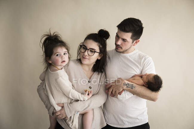 Millenial Hipster-Familie mit Neugeborenem und Kleinkind mit Sahne-Hintergrund — Stockfoto