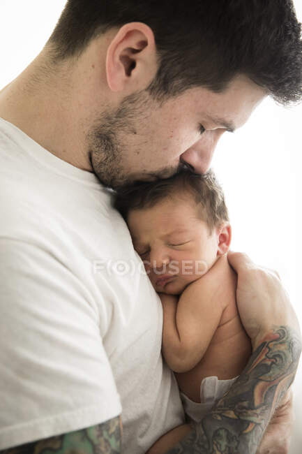 Отец держит сына на бежевом фоне — стоковое фото