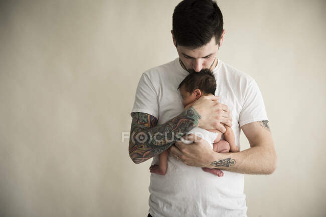 Отец держит сына на бежевом фоне — стоковое фото