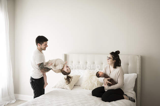 Retrato de família feliz sentado na cama, se divertindo juntos — Fotografia de Stock