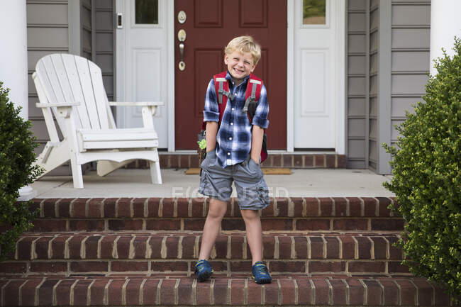 Bashful, sorrindo, loira menino fica em passos com as mãos em bolsos — Fotografia de Stock