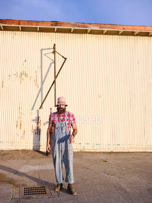 Чоловік, одягнений в іншу моду, стоїть у промисловому приміщенні.. — стокове фото