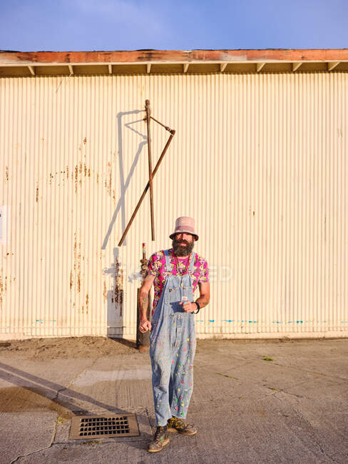 Ein alternativ gekleideter Mann steht in einem industriellen Umfeld. — Stockfoto