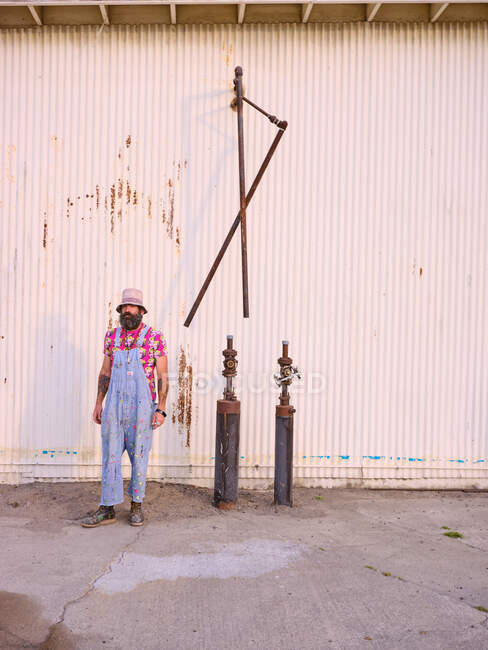 Um homem vestido com modas alternativas está em um ambiente industrial. — Fotografia de Stock