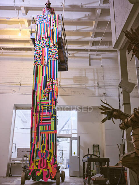 Artista instala gran tapiz de colores de un elevador de tijera. — Stock Photo