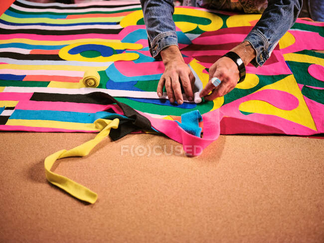 Un artista trabaja en un tapiz de tela gigante en su estudio de arte. - foto de stock