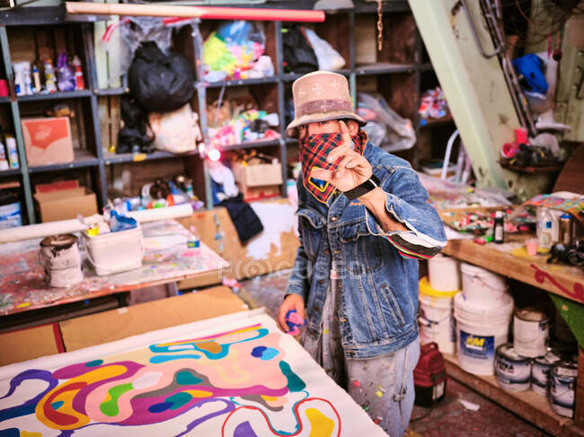 Um artista com rosto cobrindo obras em seu estúdio de arte. — Fotografia de Stock