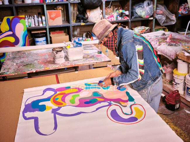 Um artista com cobertura facial cria arte em seu espaço de estúdio. — Fotografia de Stock