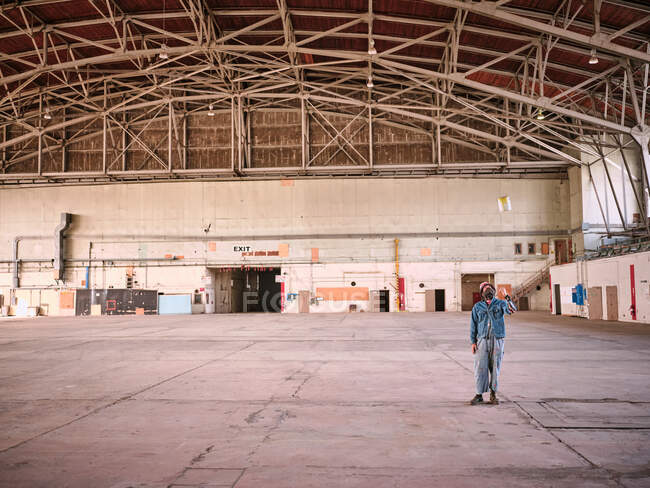 Homem vestido de ganga joga lata de tinta no ar em um prédio vazio — Fotografia de Stock