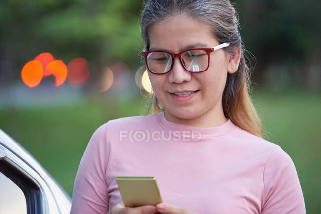 Una mujer utiliza el teléfono móvil al aire libre - foto de stock