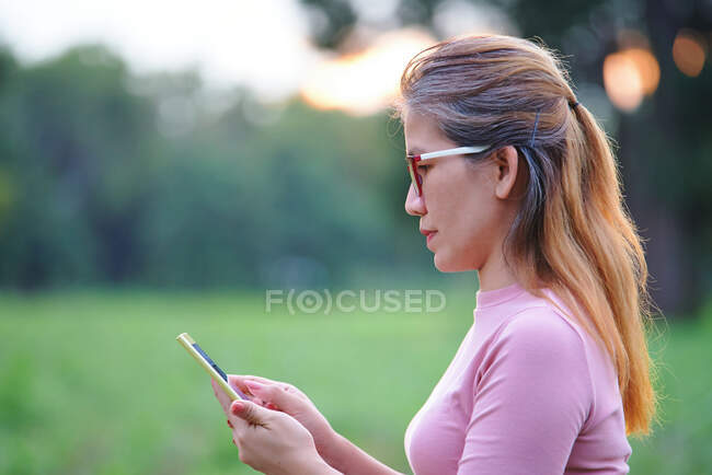 Una mujer utiliza el teléfono móvil al aire libre - foto de stock
