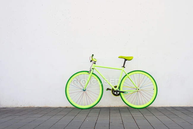 Un vélo de ville vintage vert fixe sur un mur blanc — Photo de stock