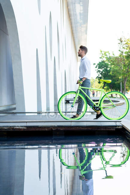 Side view of a young bearded man walking with fixie bike — Stock Photo