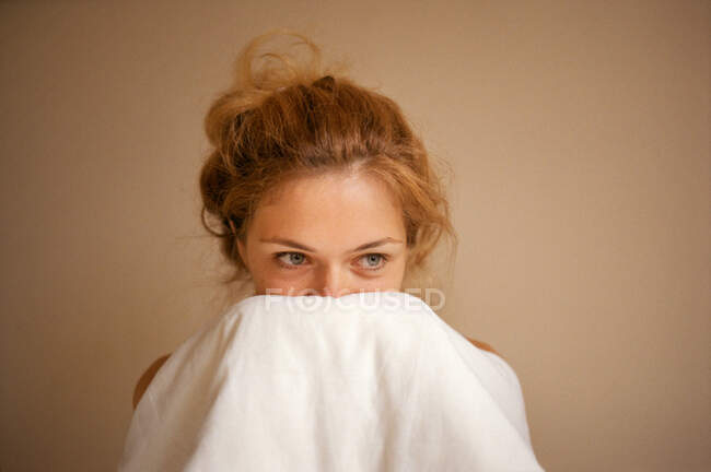 Молодая женщина закрывает лицо одеялом крупным планом.. — стоковое фото