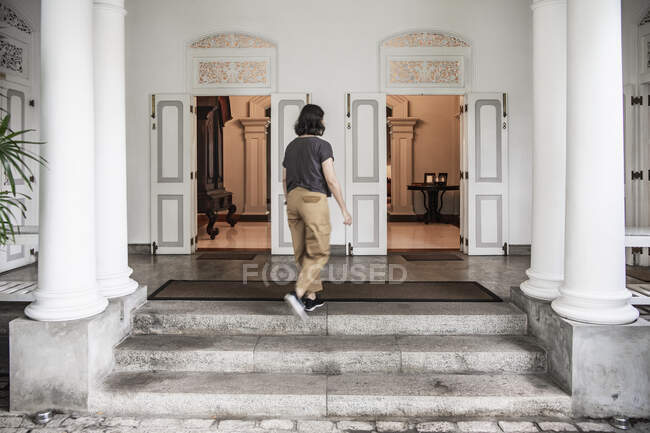 Woman walking into manour house style boutique hotel in Colombo — Stock Photo