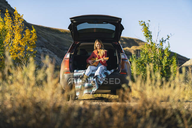 Female Artist Playing Guitar in the Country From Back of SUV — Stock Photo