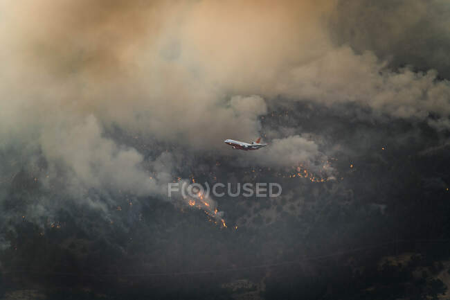 Aircraft flying over wildfire in forest — Stock Photo