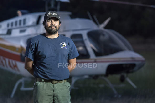 Retrato de helitack masculino confiante em pé contra helicóptero — Fotografia de Stock