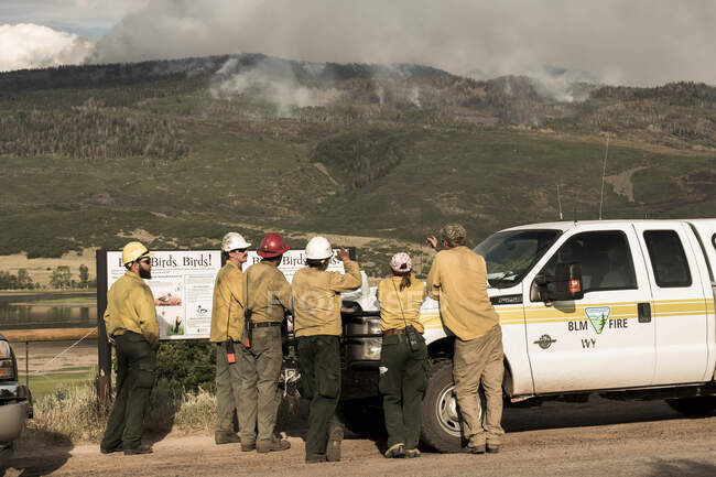 Firefighters discussing while smoke emitting from wildfire — Stock Photo