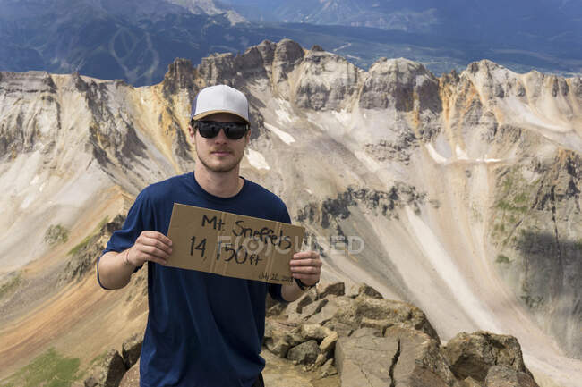 Portrait of male hiker standing with sign on Mount Sneffels — Stock Photo