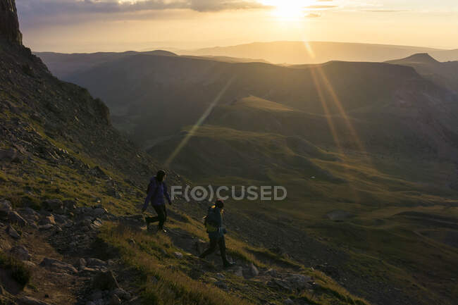 Caminhadas femininas na montanha durante o nascer do sol — Fotografia de Stock