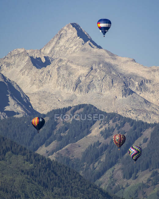 Globos de aire caliente volando contra la montaña - foto de stock