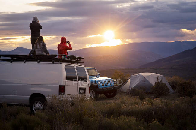 Amigos olhando para a vista enquanto de van durante o pôr do sol — Fotografia de Stock
