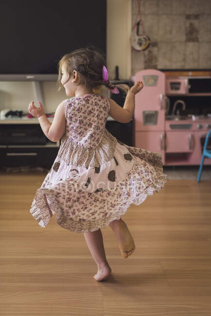 Joyous 4 yr old in tiered dress dancing barefoot on hardwood floor — Stock Photo