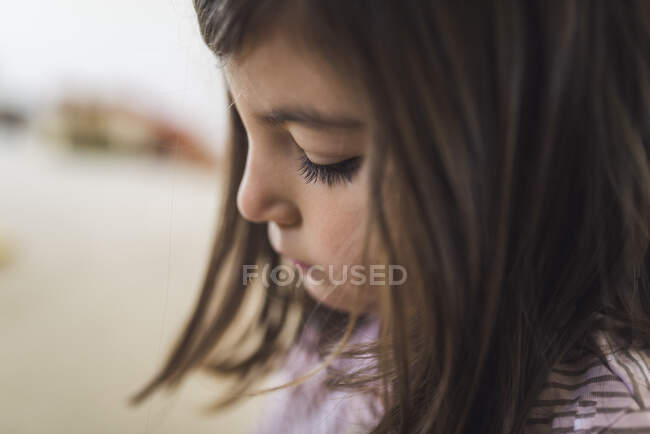 Cabeza de niña seria de 6 años con cabello oscuro y pestañas gruesas - foto de stock