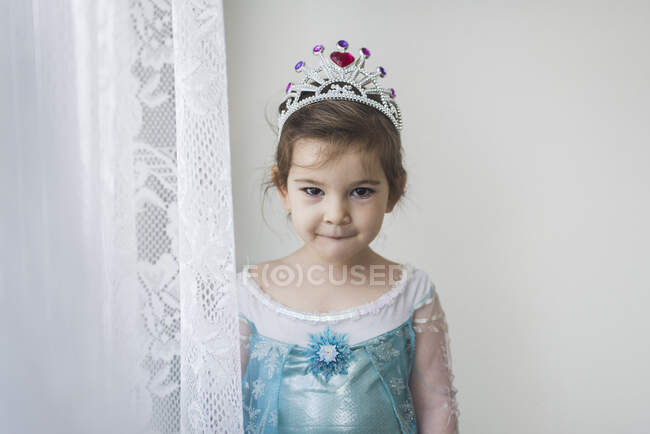 4 ans en robe de princesse debout par rideau de dentelle portant la tiare — Photo de stock