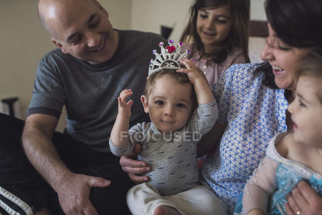 Счастливая семья с мамой, папой, двумя девочками и ребенком в костюме короны — стоковое фото