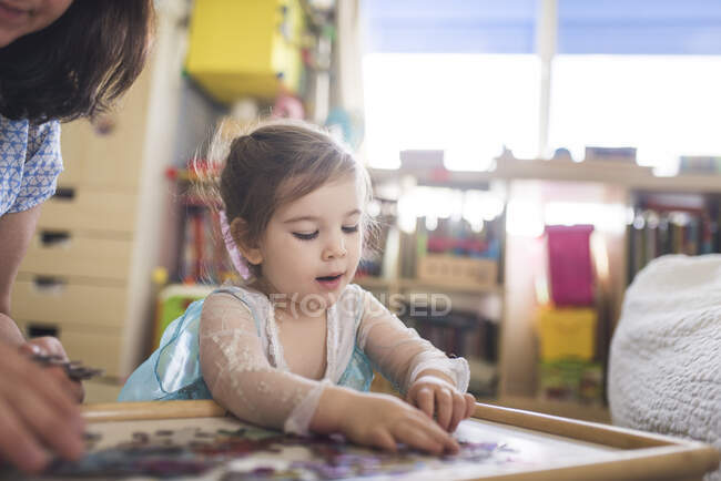 4 ans vieille fille travaillant sur un puzzle dans la salle de jeux avec l'aide de maman — Photo de stock