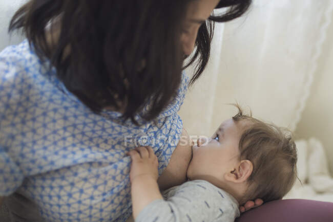Mutter starrt beim Stillen zufriedenes Baby mit offenen Augen an — Stockfoto