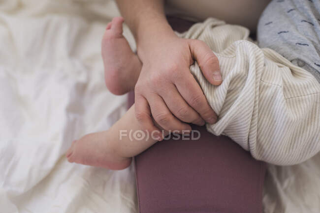 Драгоценные крошечные босые детские ноги нежно держатся за руку матери — стоковое фото