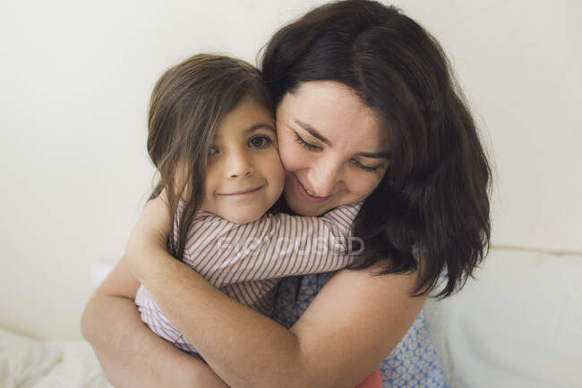 Улыбающаяся мать 30-ти лет, обнимающая счастливую 6-летнюю дочь — стоковое фото