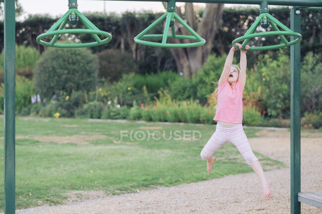 Young girl swinging on playground equipment at the park — Stock Photo