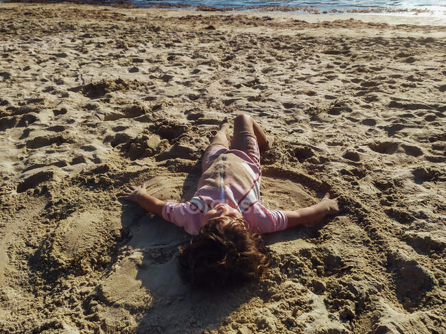 Маленький ребенок лежит на песчаном пляже — стоковое фото