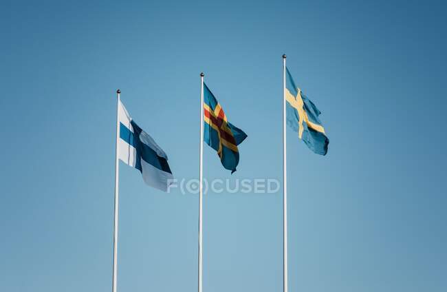 3 скандинавских флага, летящих вместе против голубого неба в Финляндии — стоковое фото