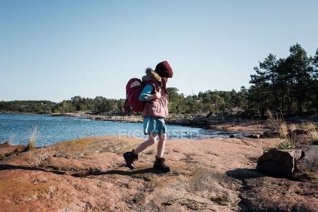 Junges Mädchen wandert mit Rucksack auf Felsen in Finnland am Meer — Stockfoto