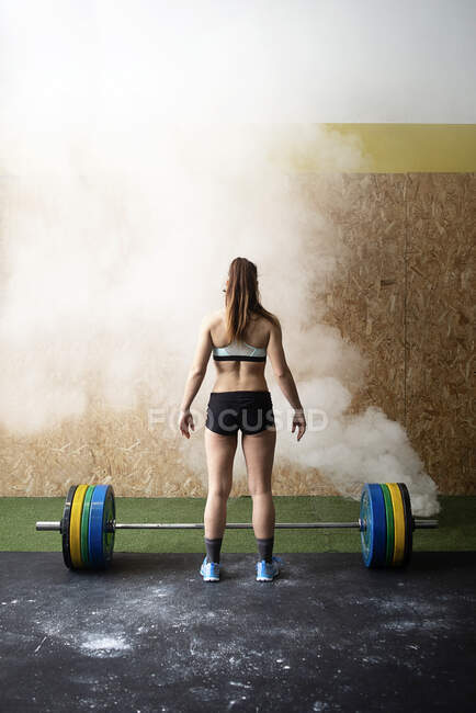 Вид ззаду жінки, що піднімає штангу в спортзалі — стокове фото