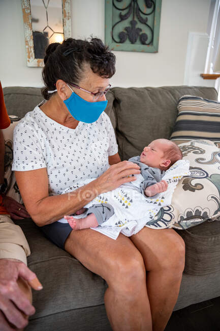 Frau mit Mundschutz hält neugeborenes Baby. — Stockfoto