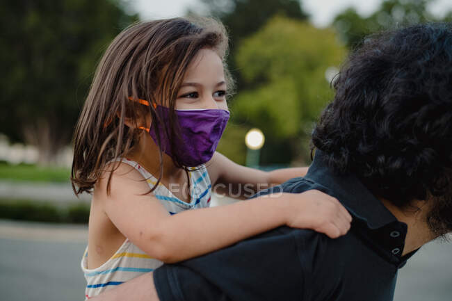 Glückliches Kind reitet huckepack mit Papa und trägt Gesichtsmaske — Stockfoto