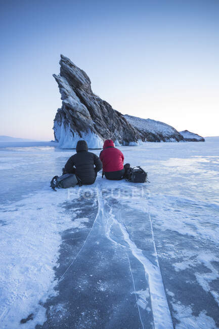 Dos pohotographers que esperan la puesta del sol en el lago baikal. - foto de stock