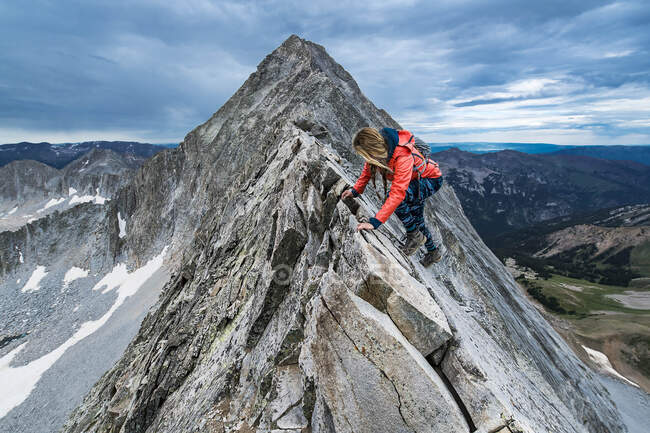 Female hiker climbing mountain peak during winter — Stock Photo