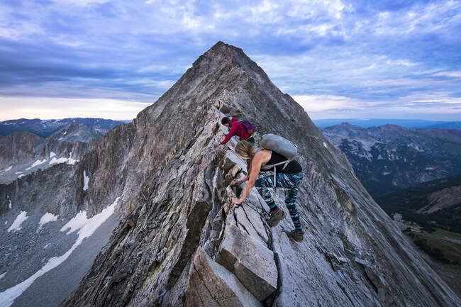 Женщины-туристы поднимаются на гору на закате — стоковое фото