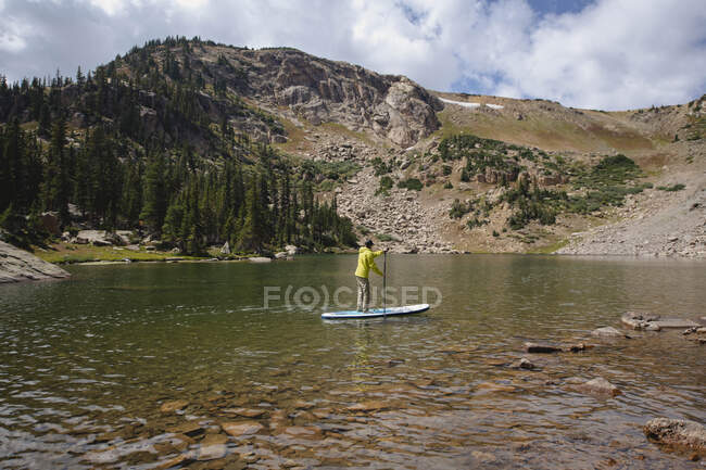 Homem paddleboarding no lago durante o verão — Fotografia de Stock